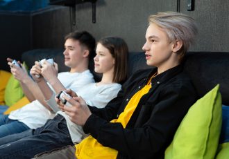Group of friends of teenagers, playing video games on a console in a game club.